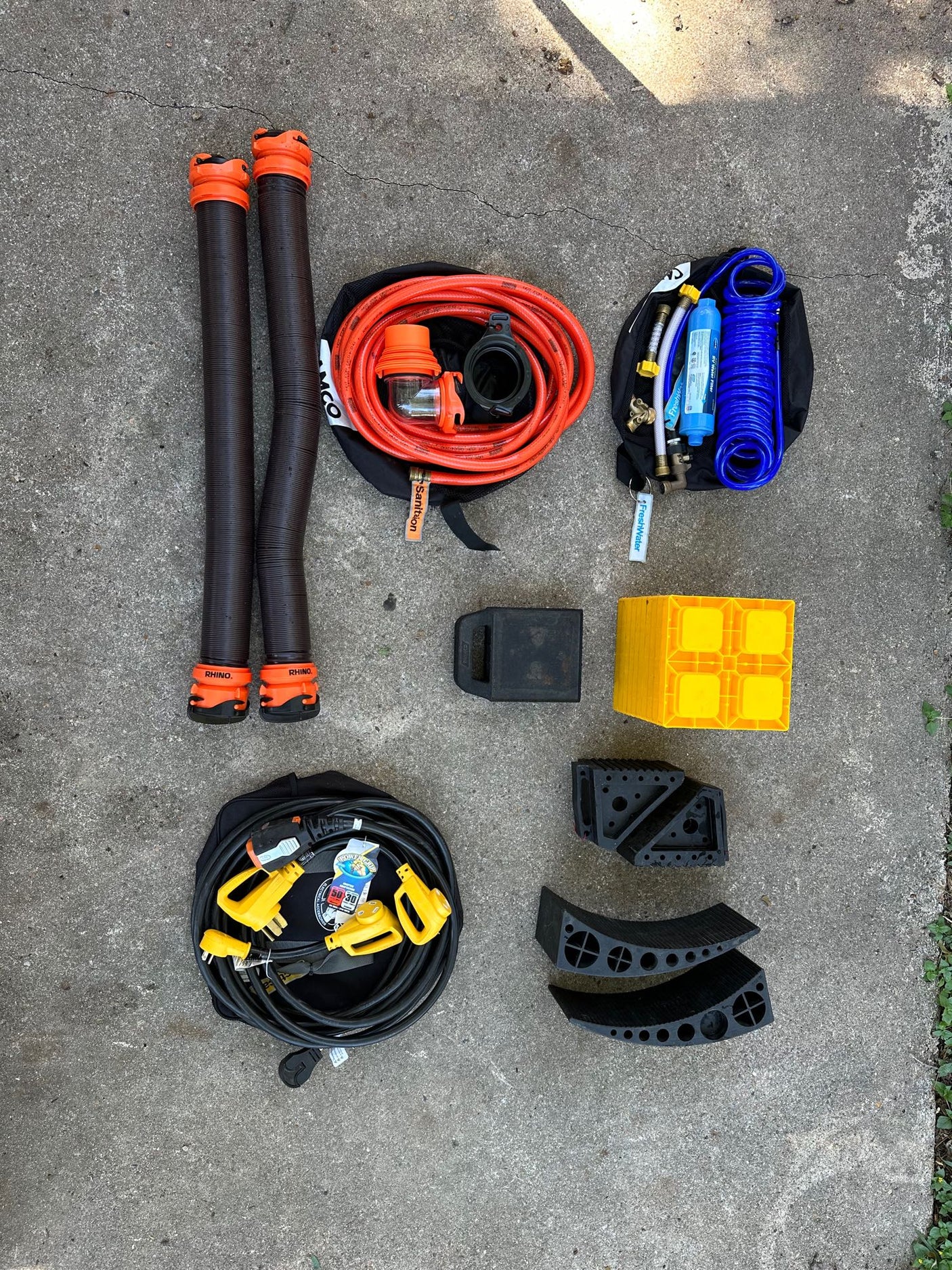 Essential RV rental gear: sewer & water hoses, power cords, filters, and leveling blocks for a smooth trip.