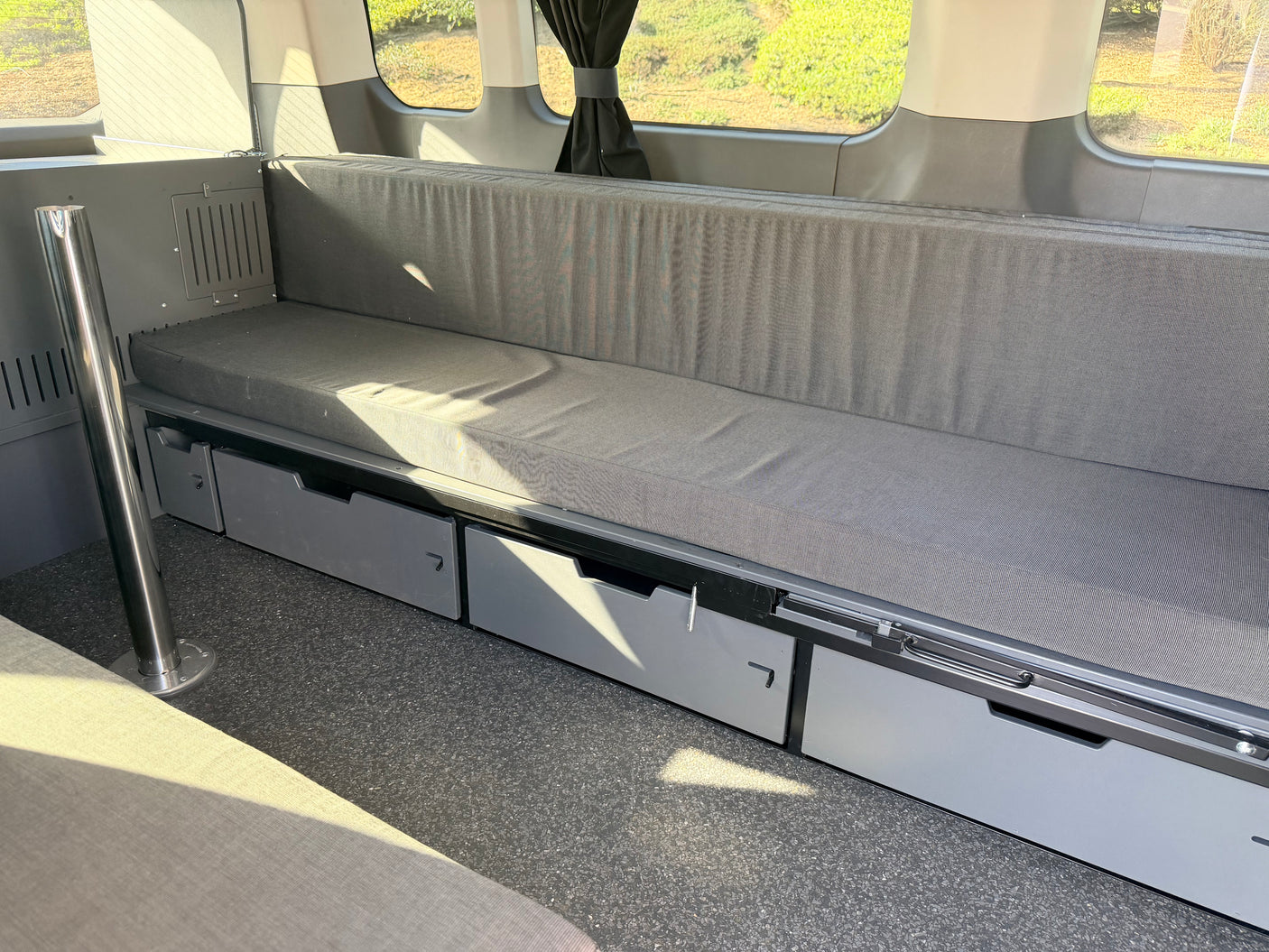 RV rental camper van: efficient interior with a long bench seat, storage drawers, and bright windows. Ideal for travel.
