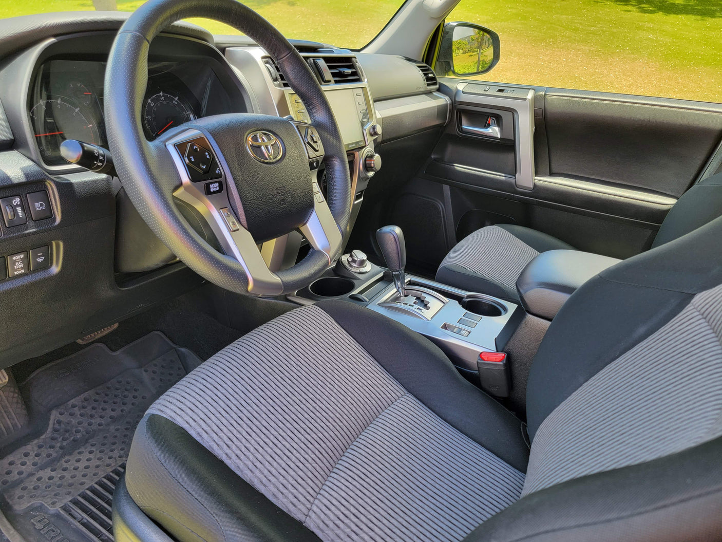 Interior view of a modern SUV's driver side, showing the steering wheel, dashboard, shifter, and fabric seats. Great for an rv rental adventure.