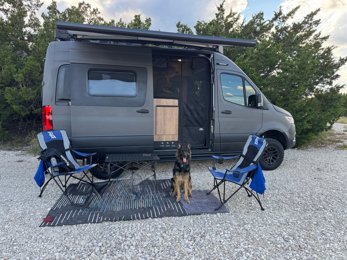 perfect for a van life adventure.|A gray camper van RV rental parked on gravel with an outdoor setup — photo 2