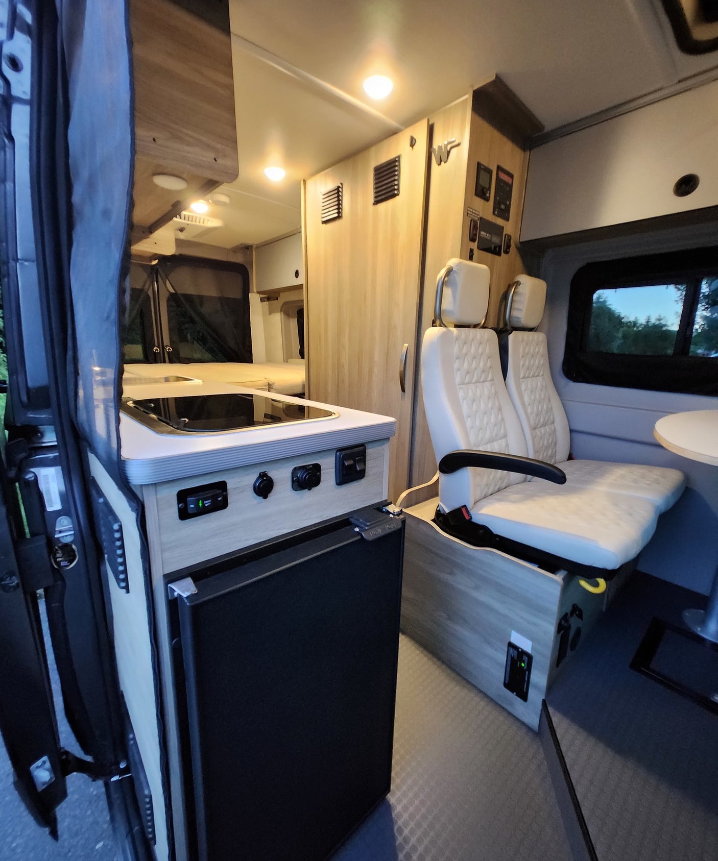 and a convertible lounge.|RV rental: Inside a modern camper van featuring swivel seating