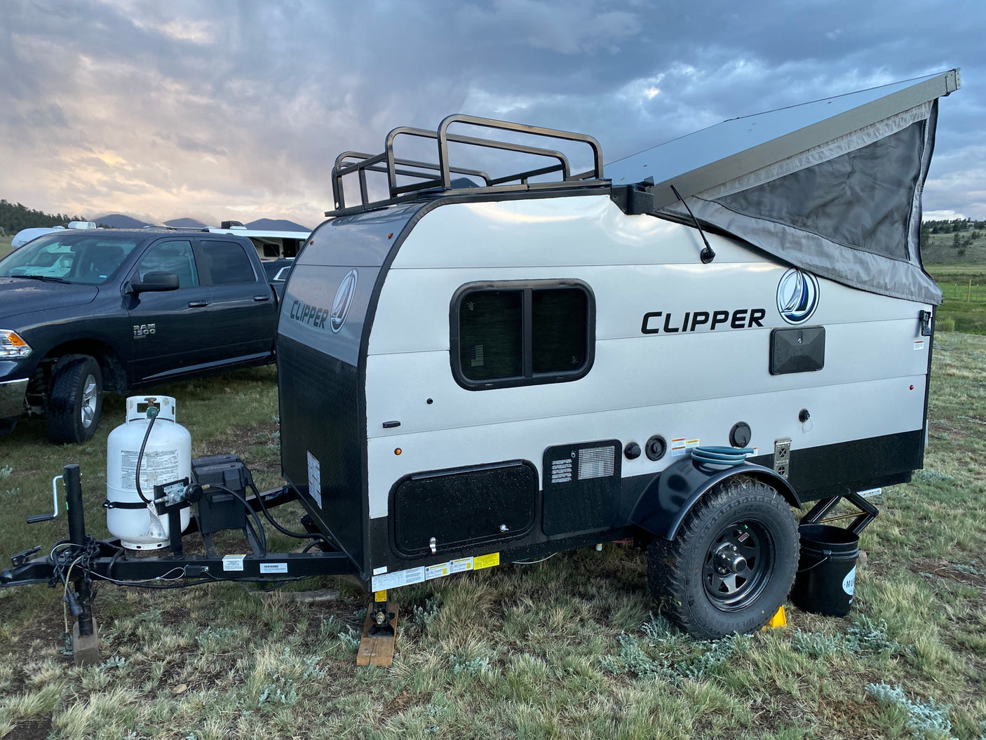 This Clipper pop-top travel trailer rv rental is ready for outdoor adventure, parked under a cloudy sky.