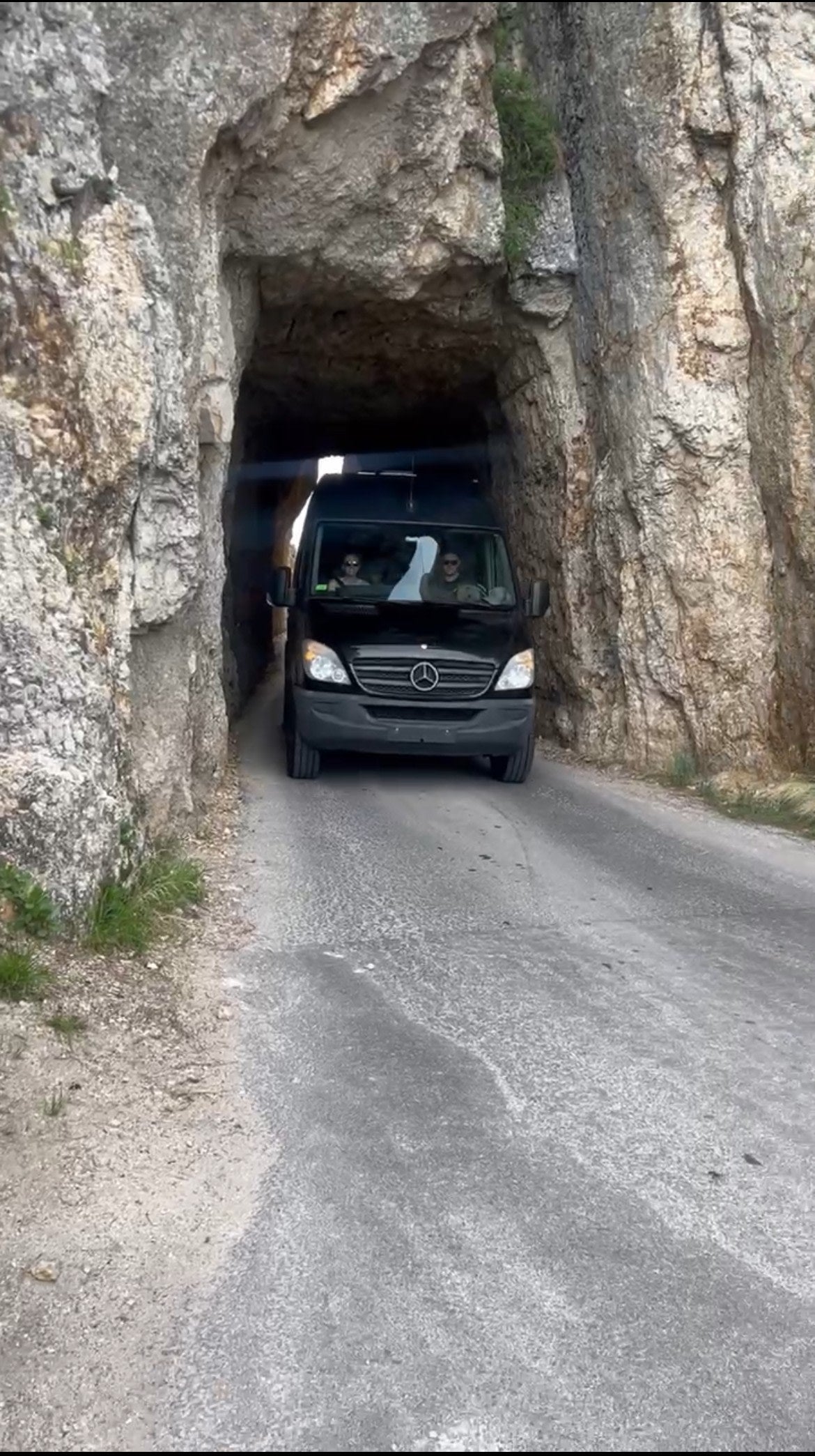 parked on a scenic mountain road. Perfect for road trips.|A black Sprinter van rv rental is parked at site 10 with outdoor seating and lush trees.|This black Sprinter-style van — photo 2