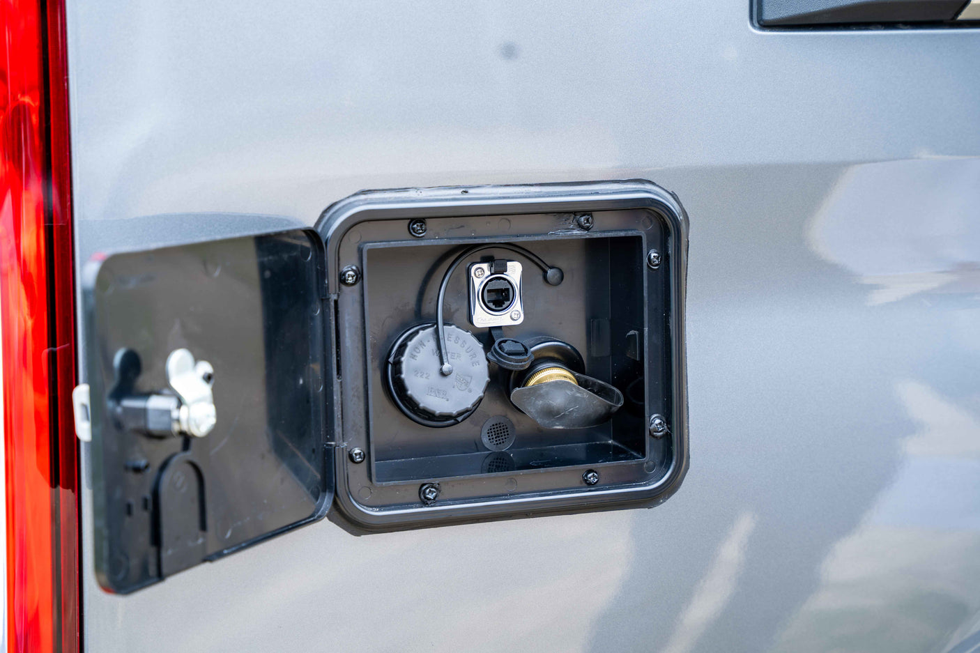 RV rental: Exterior utility compartment with non-pressure water fill, data port, and other hookups visible.
