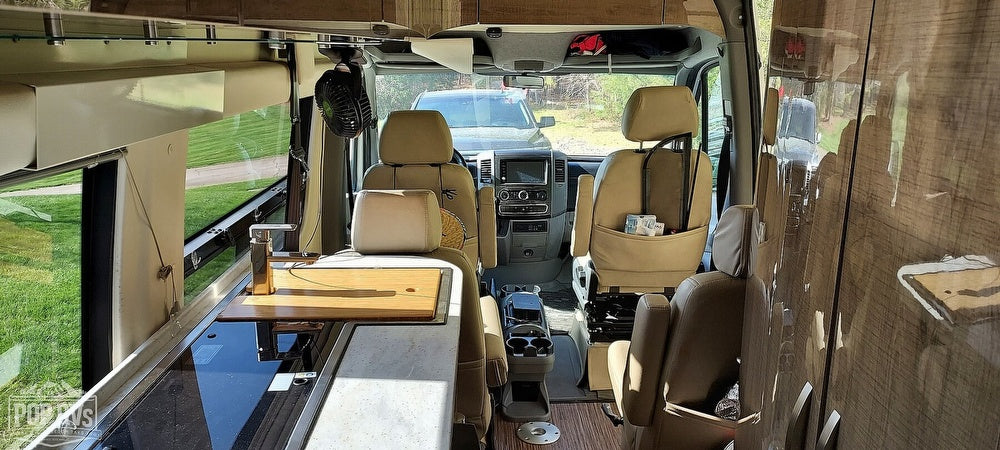 Spacious RV rental interior showing front cockpit, swivel seats, and modern kitchen counter. Perfect for road trips.