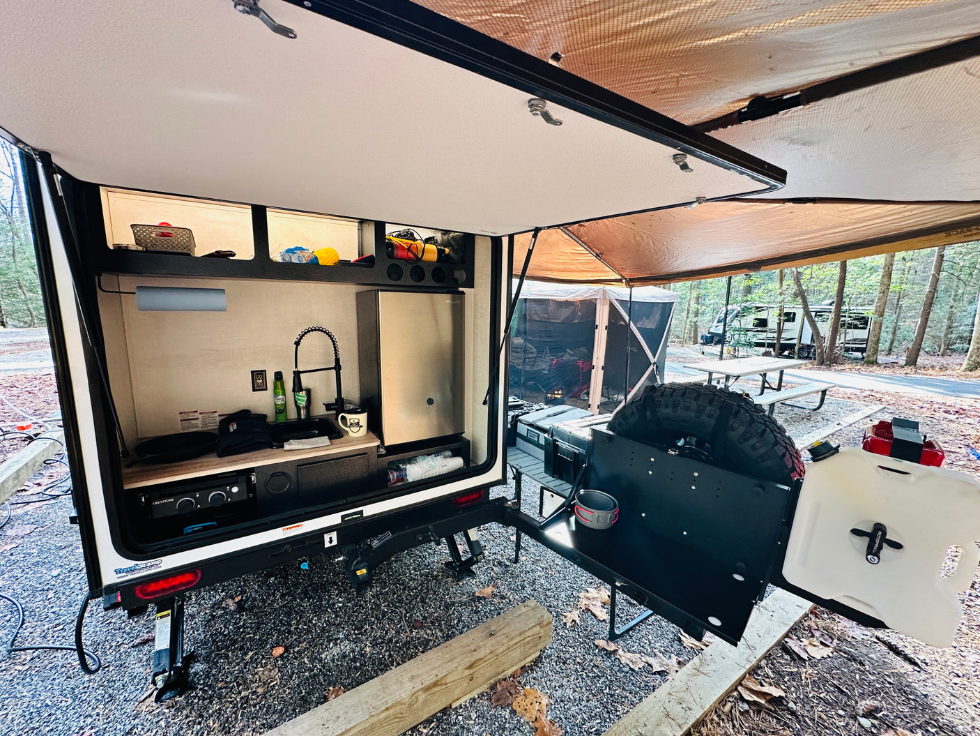 Camping with this compact RV rental! Enjoy the outdoor kitchen, sink, fridge, and shaded awning at your campsite.