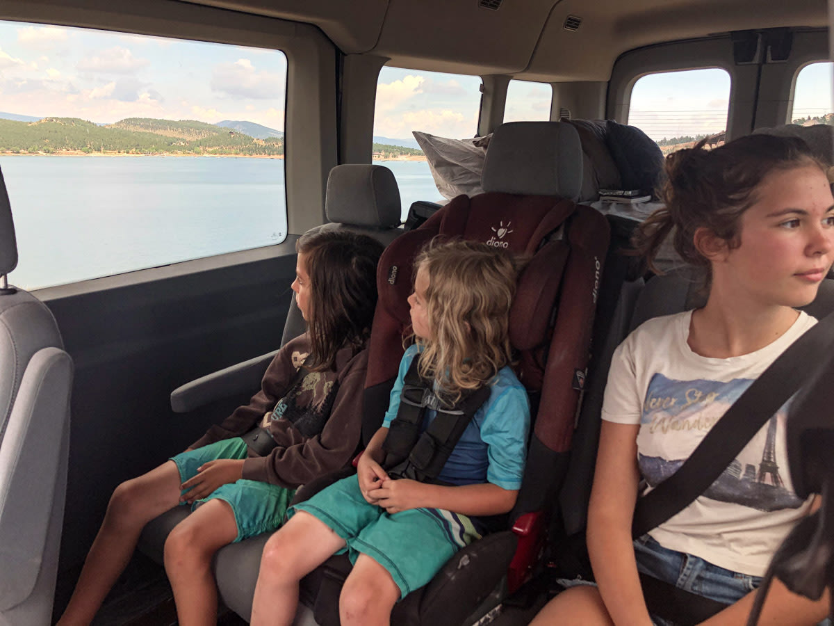 and clever storage for your travels.|Three kids in an RV rental looking out at a large lake and distant hills on a scenic family road trip.|Smiling couple chats