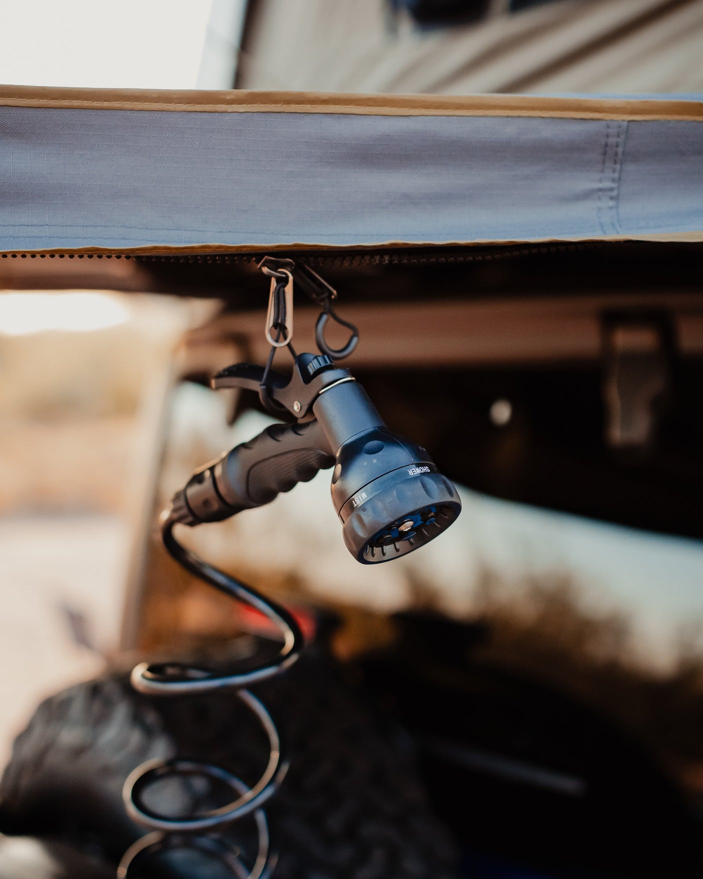 Outdoor shower setup for an rv rental: a multi-setting spray nozzle hangs from carabiners, ready for adventure.