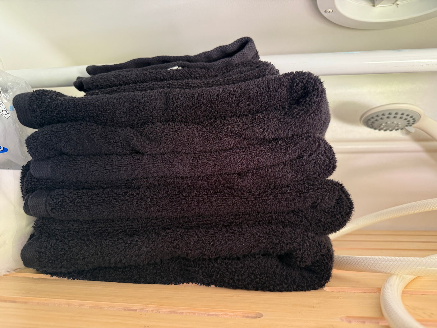 Neatly stacked black towels provide comfort in this RV rental bathroom. A shower is visible.