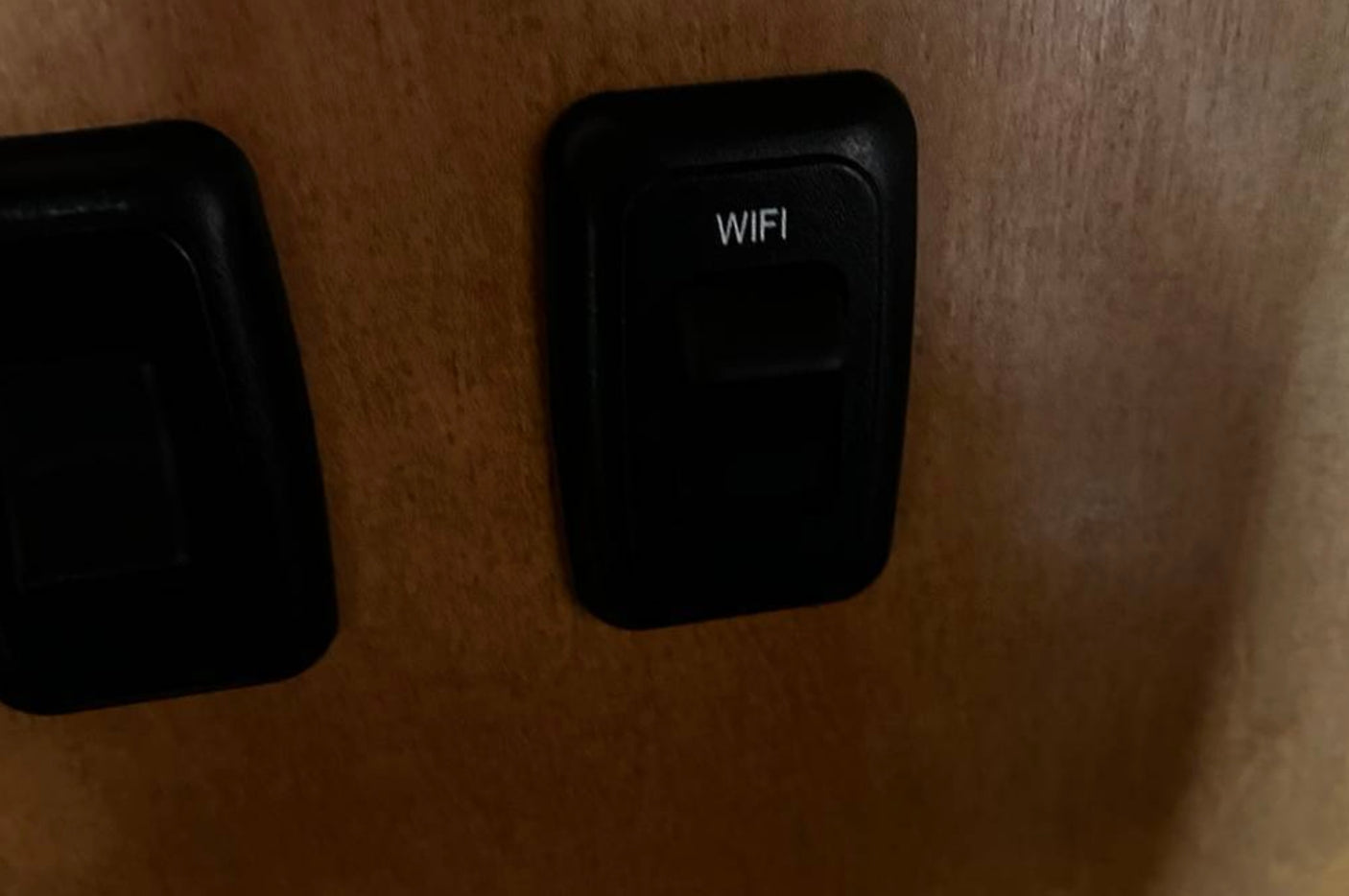 Close-up of a "WIFI" button on a wood panel in an RV rental, providing internet access for occupants.