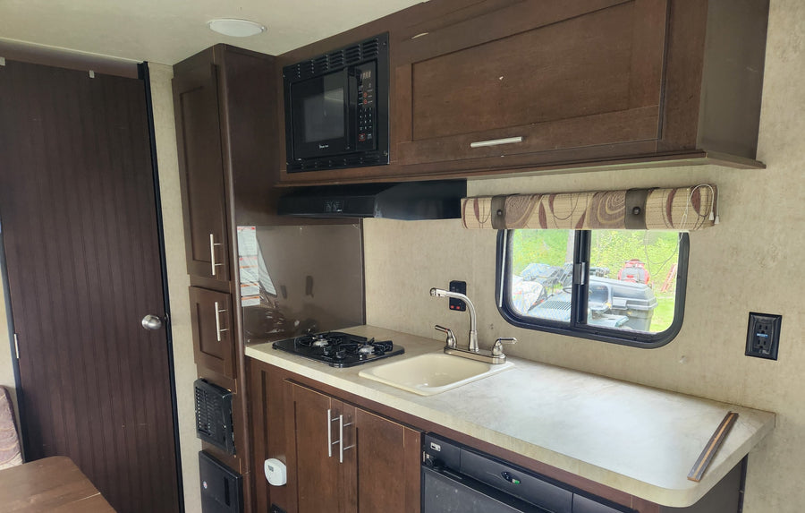 and fire extinguisher near the door.|Rear of a beige Wolf Pup travel trailer