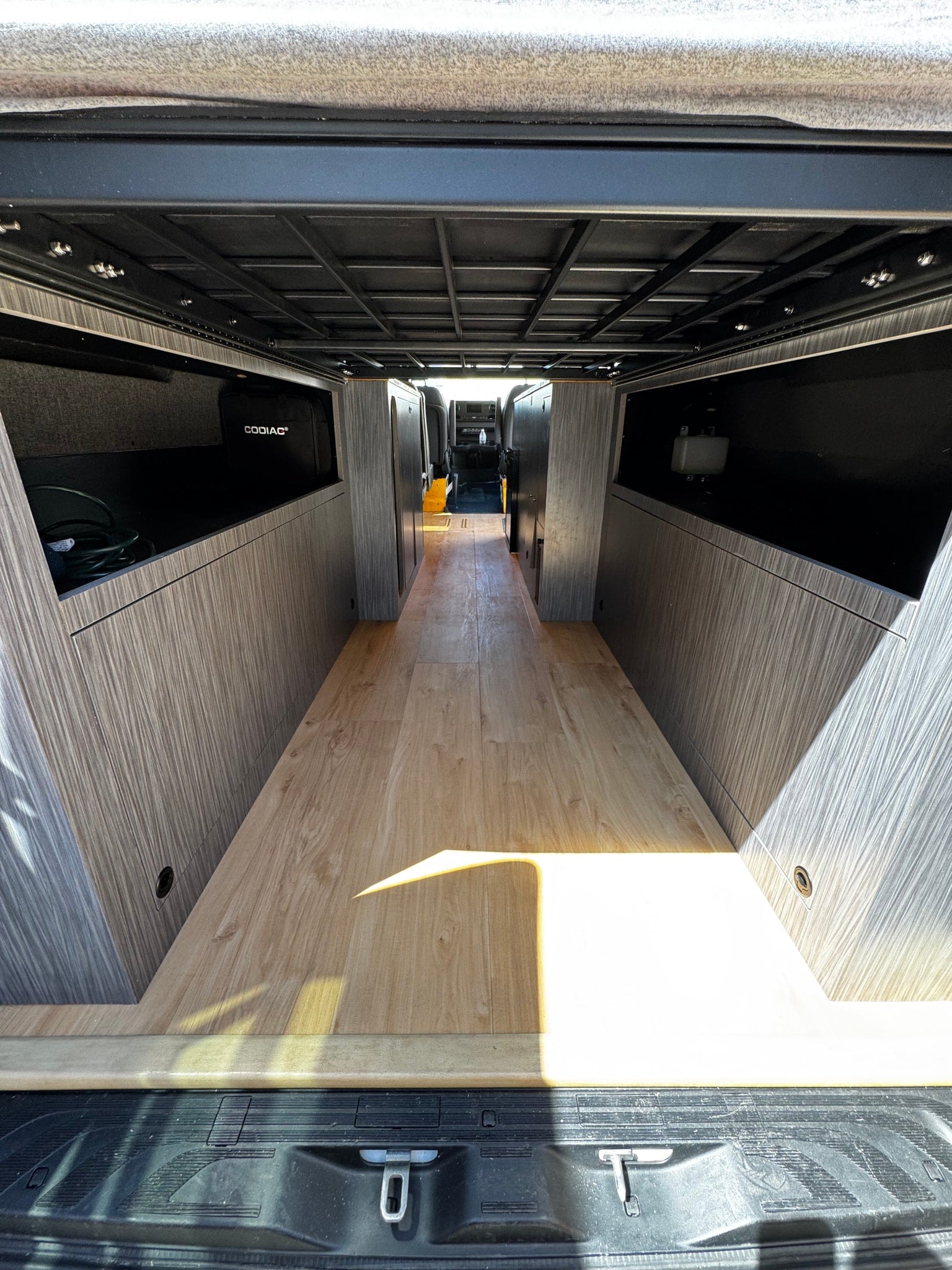 Spacious RV rental interior with wood floor, custom storage, and overhead frame for comfortable mobile living.
