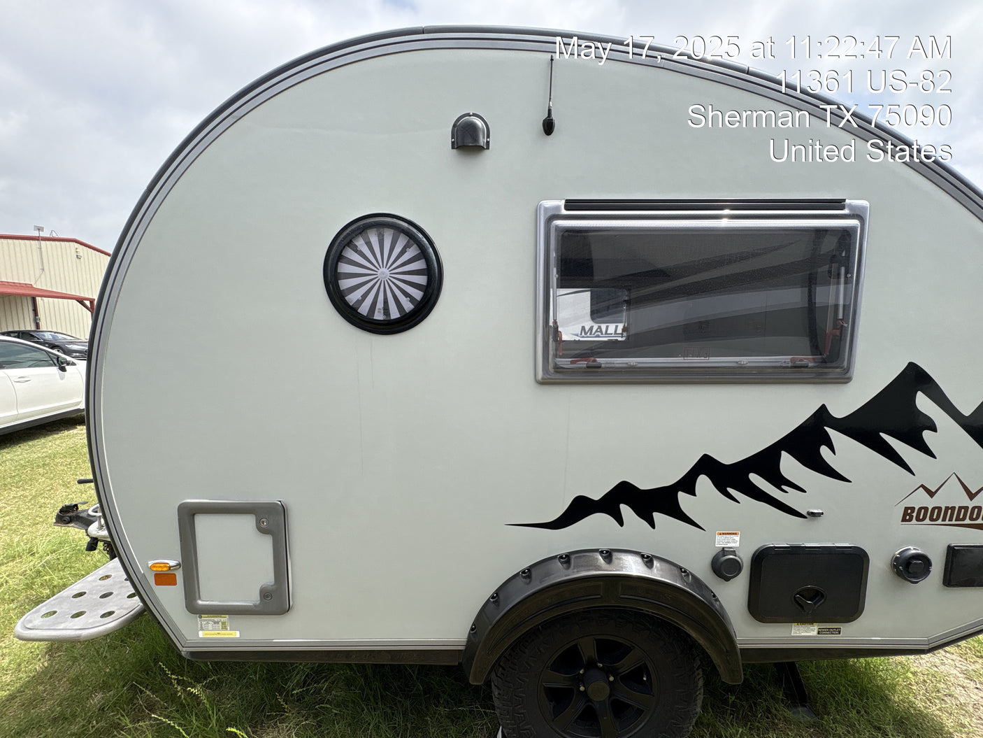 Light gray **rv rental** travel trailer with black mountain graphics and unique round window, ready for your next outdoor adventure.