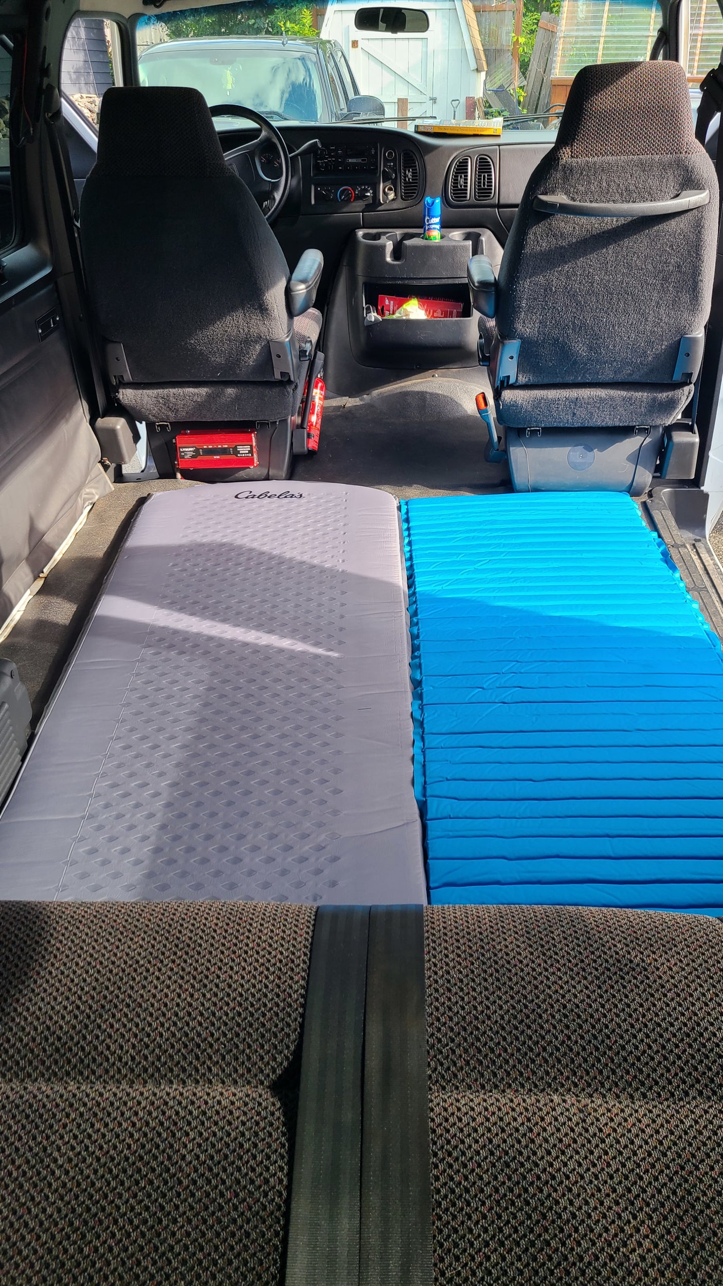 Van interior converted for travel, featuring dual sleeping pads. Ideal RV rental choice!