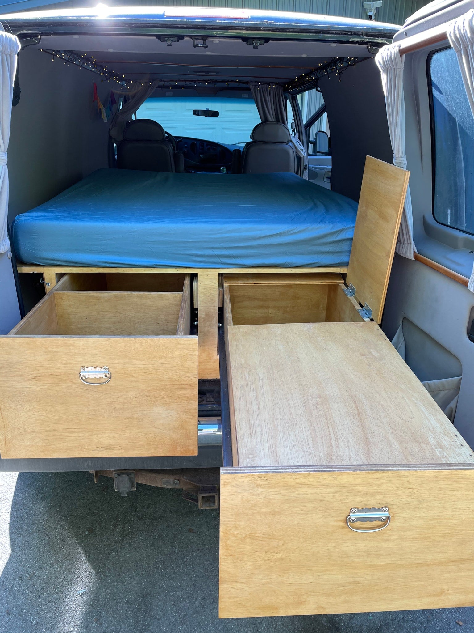 Inside an RV rental: a built-in bed over open pull-out drawers and lift-up storage in the rear.