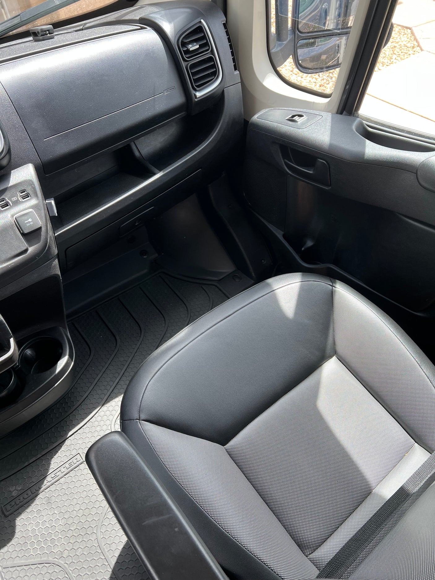 Ram Promaster RV rental interior: passenger dashboard, seat, and patterned rubber floor mat.