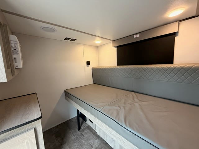 This modern RV rental interior features a versatile bench bed, overhead lighting, and compact storage, ideal for travel.