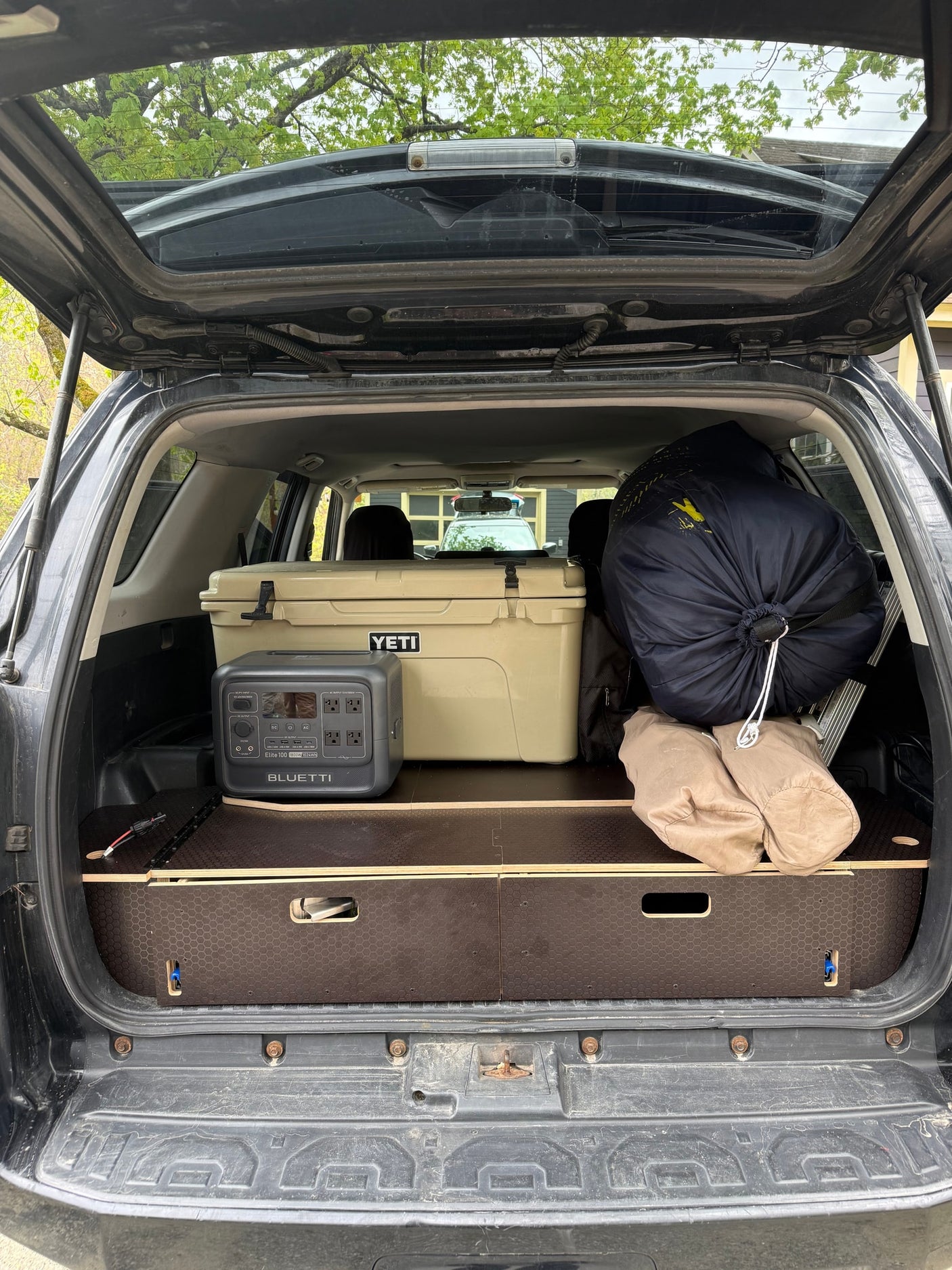 Car trunk setup with Yeti cooler, Bluetti power station, and camping gear, ideal for trips. Consider it for your next rv rental.
