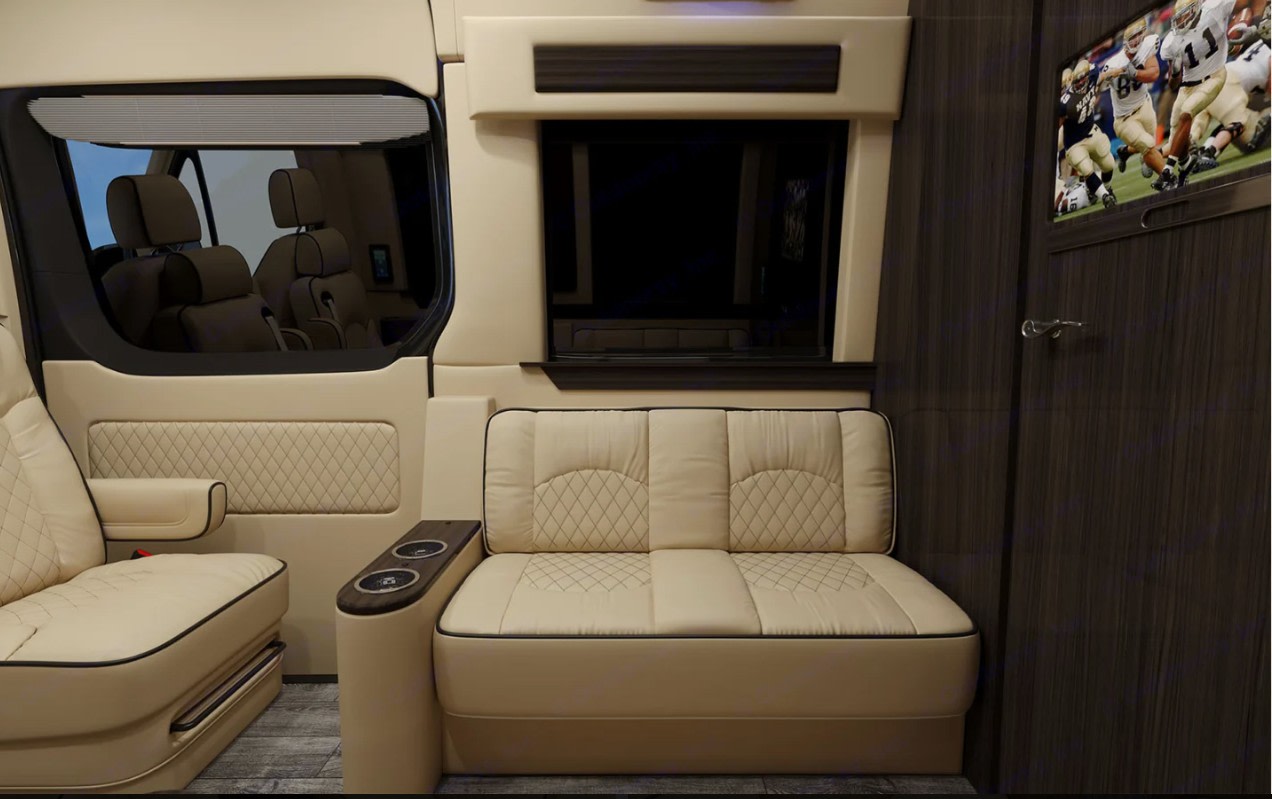 Luxury RV rental interior showcasing beige quilted leather seating, a mounted TV, and window blinds for premium travel.