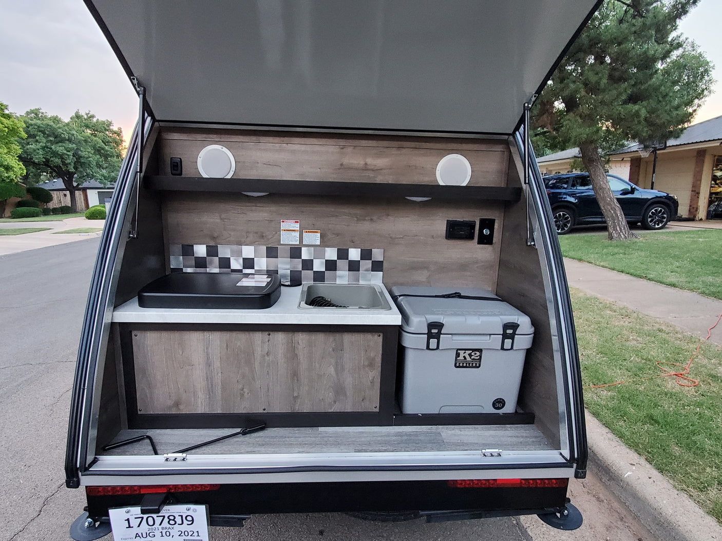 Open rear galley of an RV rental camper with outdoor kitchen: sink, stovetop, and K2 cooler, ready for camping trips.