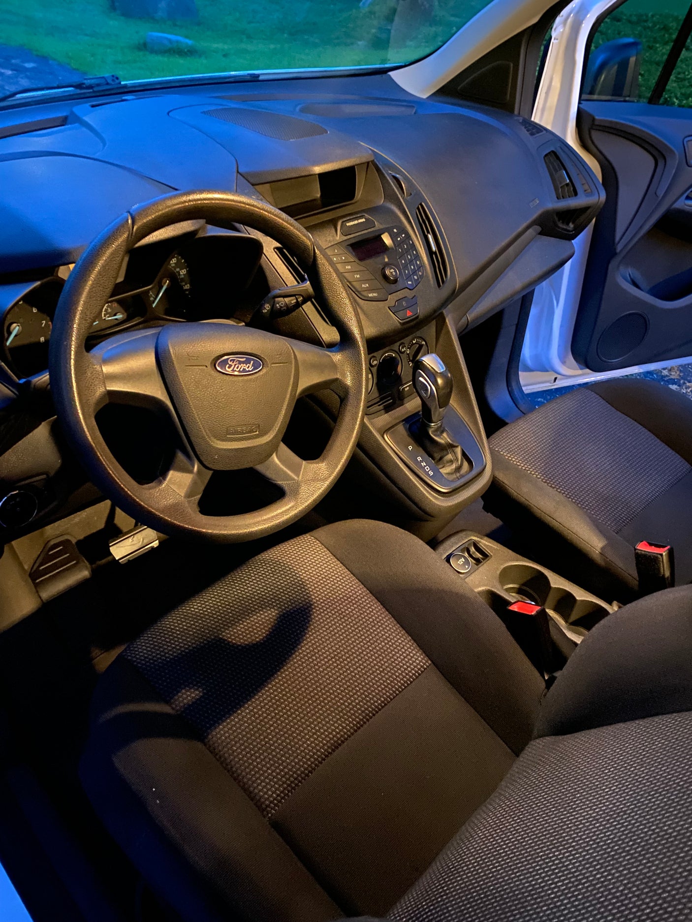 Inside a Ford van: dashboard, steering wheel, gear shift, and fabric seats. Ideal for your next compact rv rental adventure.
