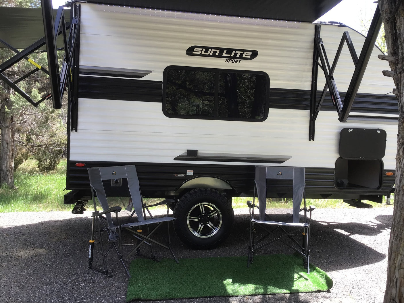 ready for adventure in nature.|Cozy rv rental setup: a white Sun Lite Sport travel trailer with an extended awning