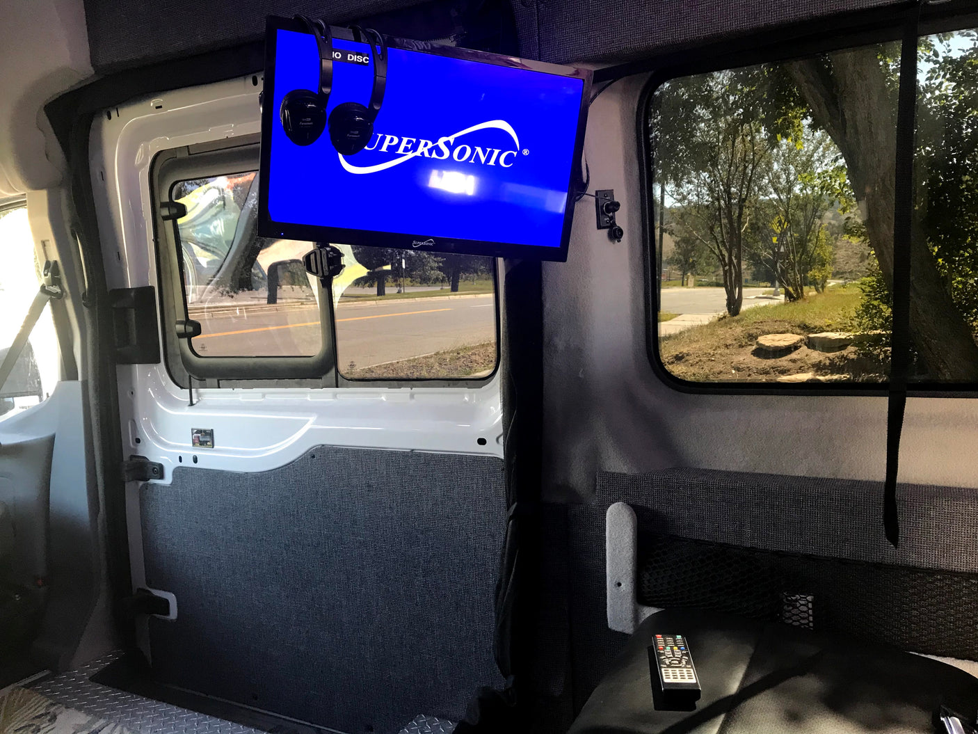 RV rental interior with mounted TV, headphones, and a view of the road, offering entertainment on the go.