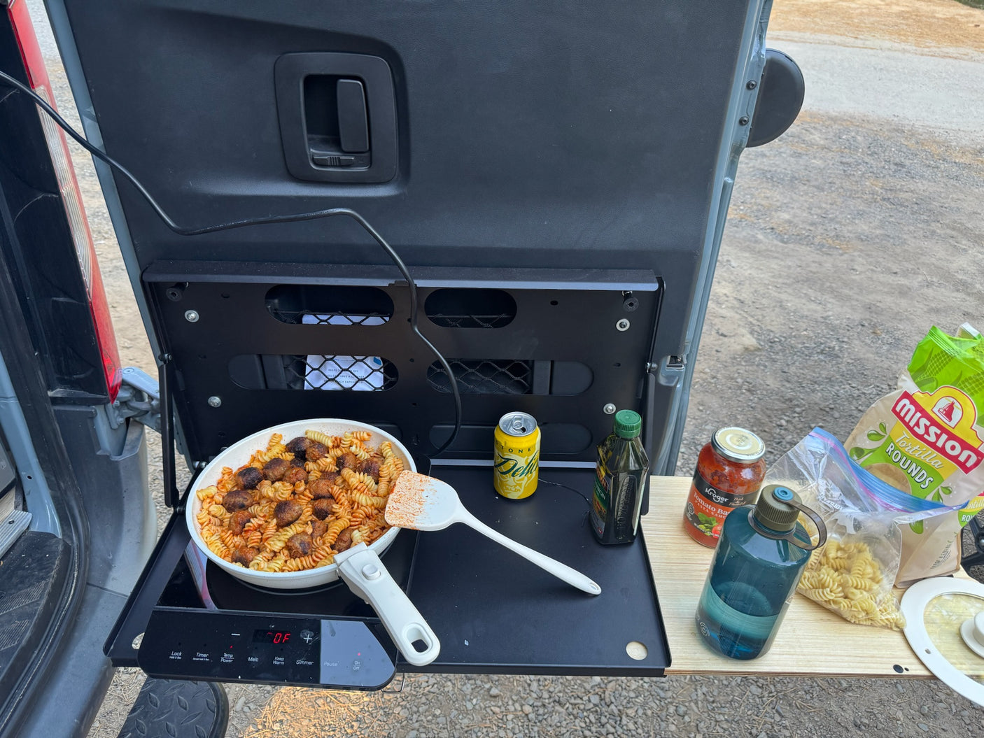Enjoying an **RV rental** adventure with a delicious **camp kitchen** meal: pasta & meatballs cooked outdoors.