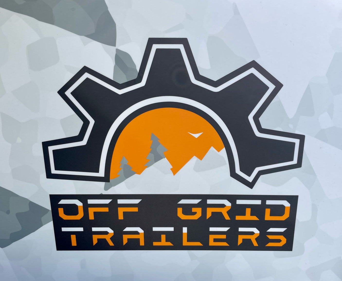 Off Grid Trailers logo: a black gear with orange, white, and gray landscape inside. White/orange text. Ideal for rugged adventure & RV rental.