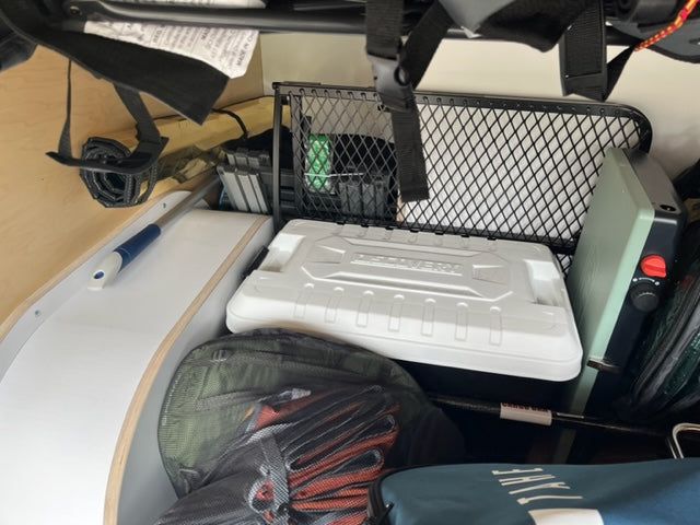Efficient RV rental storage features a Discovery cooler, portable stove, and cleaning mop, ready for travel.