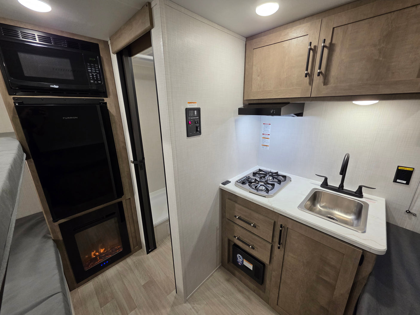 RV rental interior: Kitchen with stove, sink, microwave, fridge, and cozy electric fireplace.