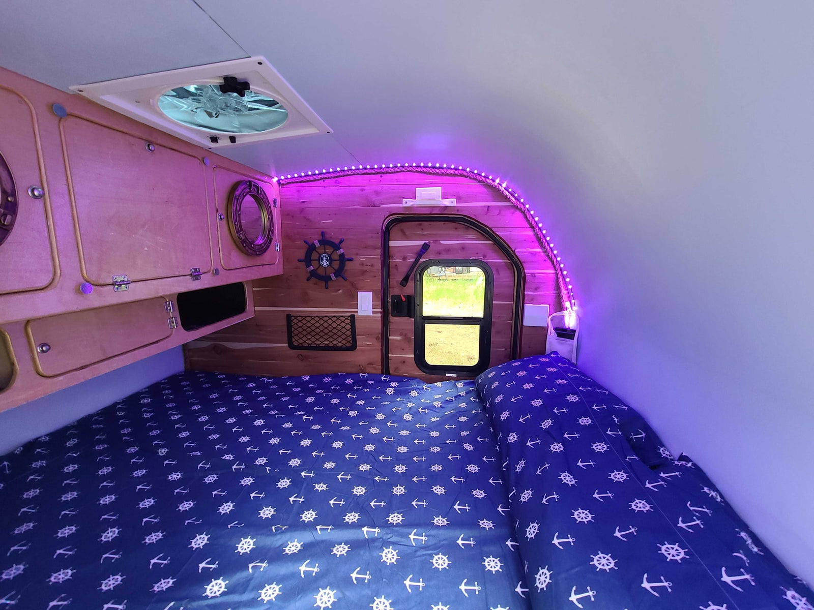 Cozy RV rental interior with nautical bedding, wood accents, and ambient purple LED lighting.
