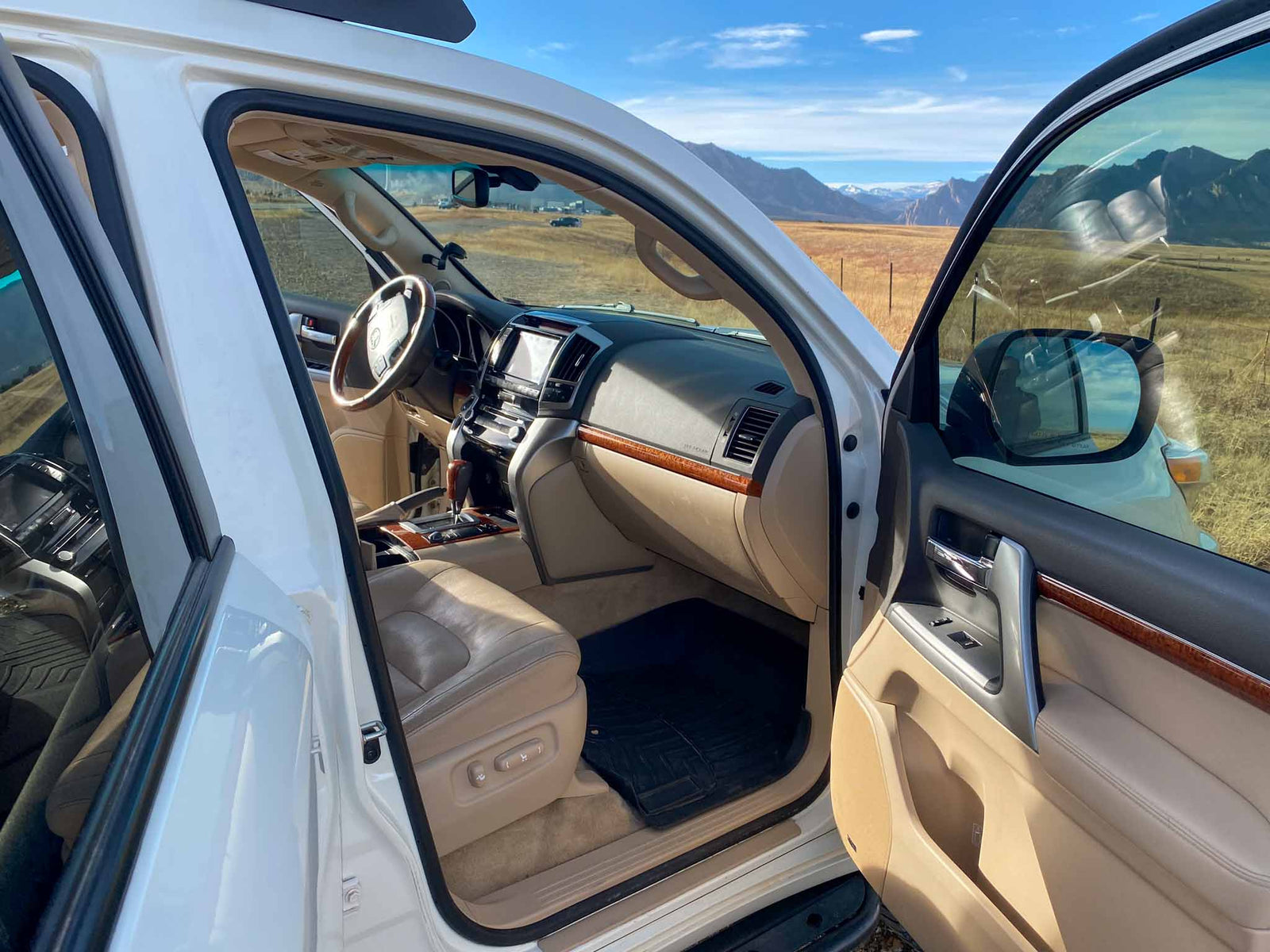 ideal for an RV rental adventure. Stunning mountains & fields ahead.|Open white SUV door shows luxury interior and mountain views