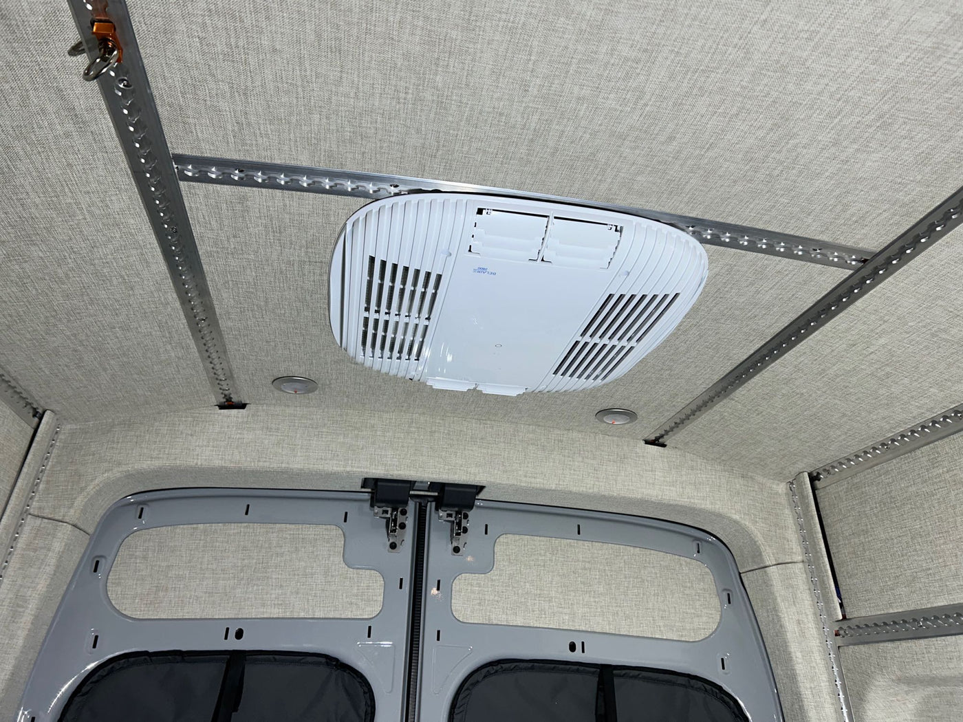 and spacious floor plan with cargo tracks.|RV rental: Van interior with a raised bed — photo 9