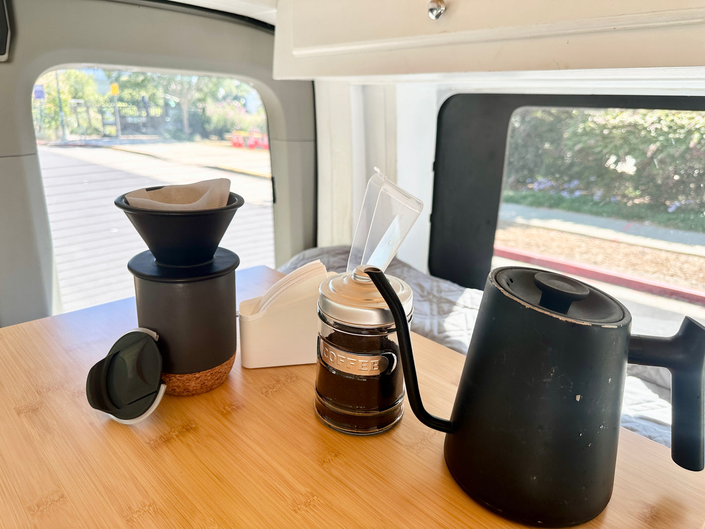 Pour-over coffee setup on a wooden table inside an RV rental, with kettle, filters, and grounds visible.