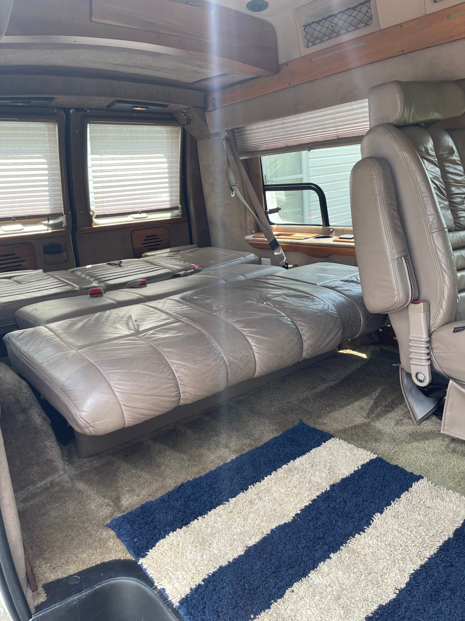 and wooden cabinetry. View of grass outside.|Inside an RV rental van with a portable LG AC unit