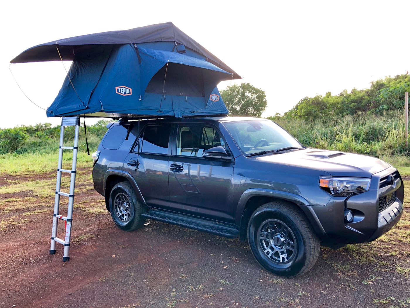 Dark gray SUV with rooftop tent & ladder, ideal for rv rental adventures on dirt road. — photo 15