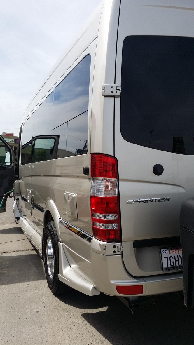 Rear three-quarter view of a light-colored Mercedes Sprinter van, likely an rv rental, with tinted windows and a California plate.
