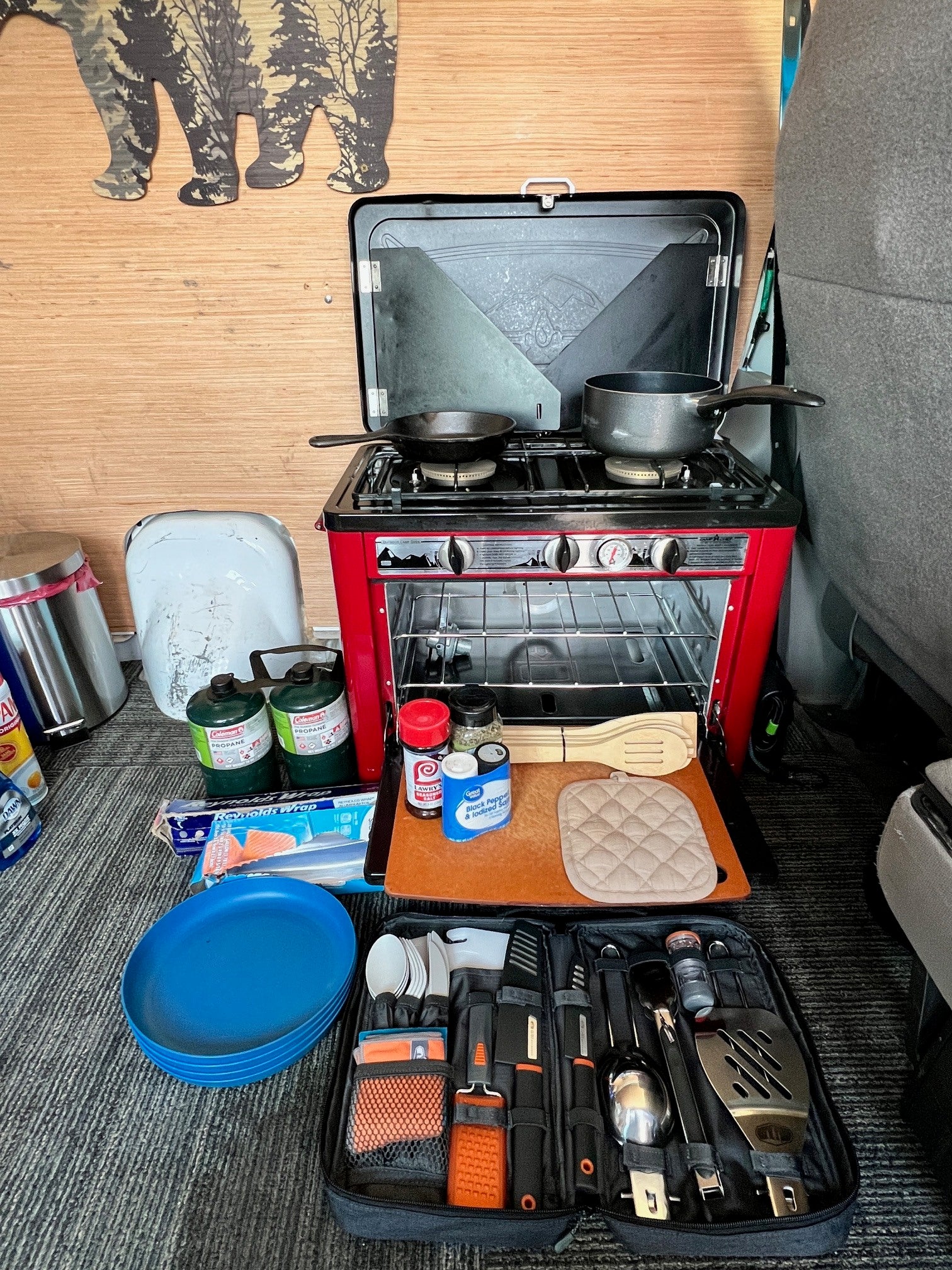 RV rental compact kitchen setup: portable stove/oven, cooking tools, and supplies for camping meals.