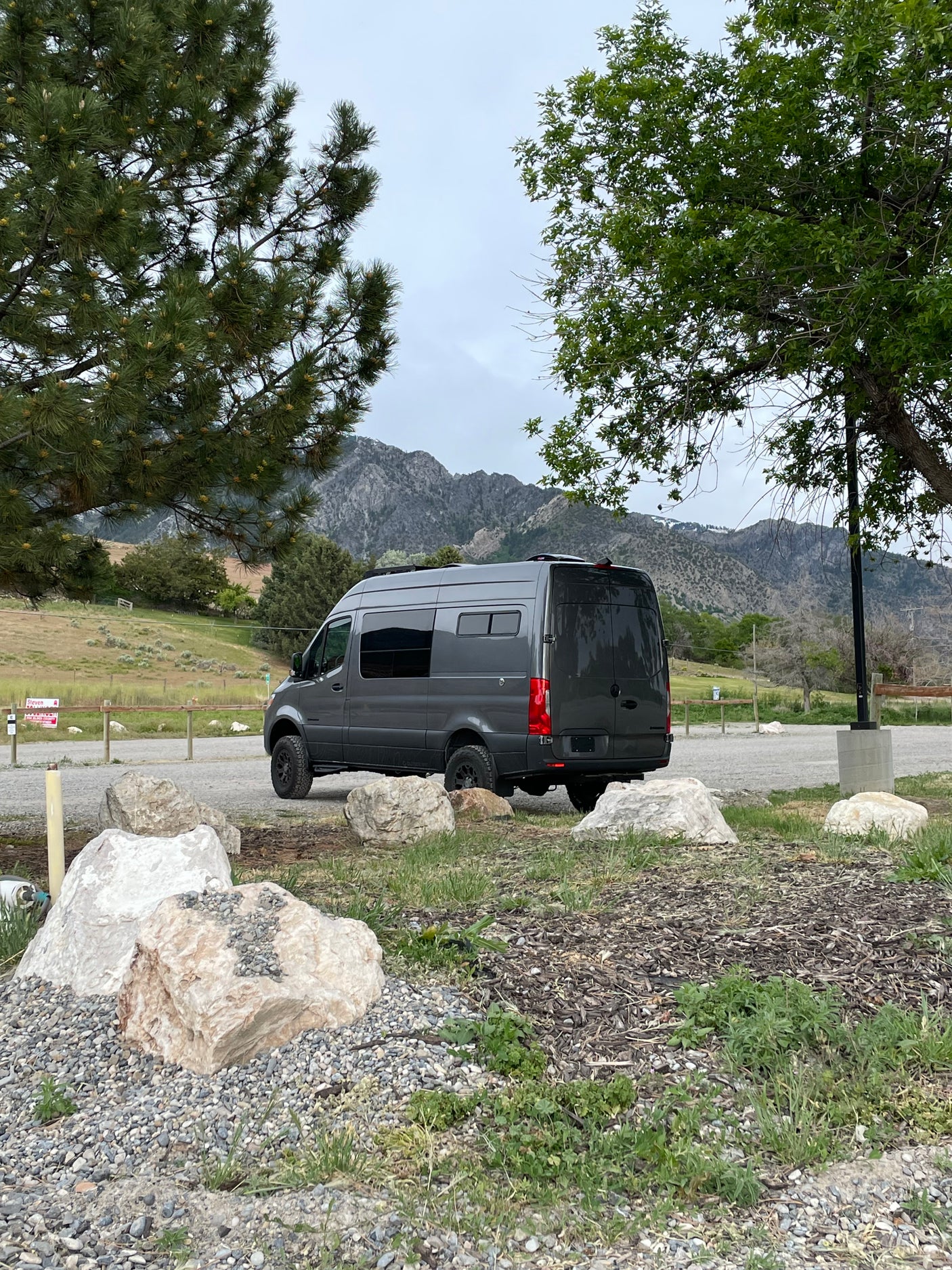 A dark gray camper van in a mountain park setting, ready for adventure. Ideal for rv rental.