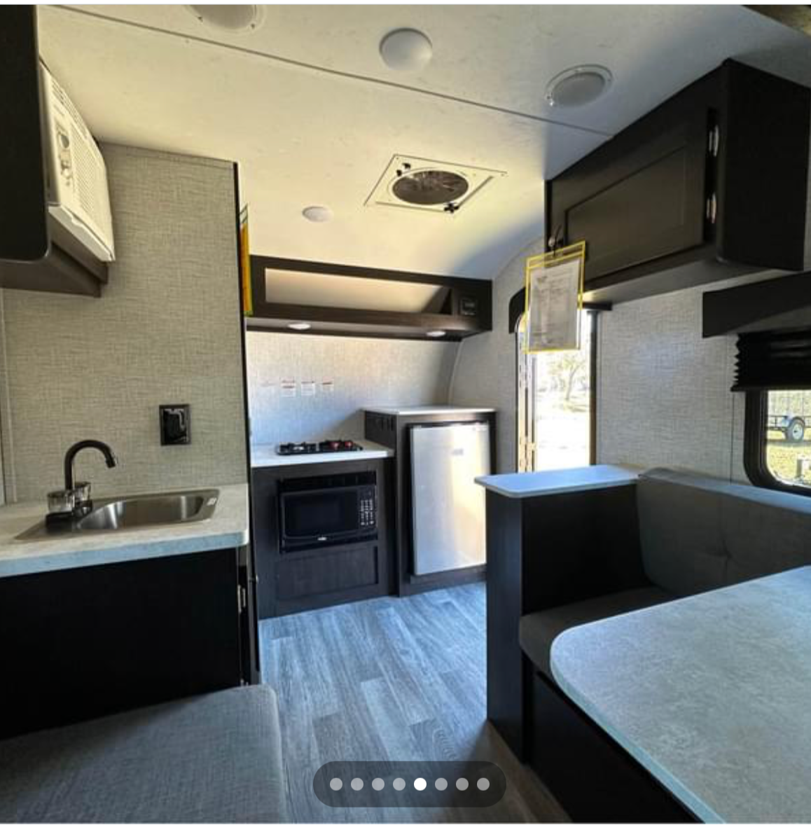 Bright rv rental interior featuring a full kitchenette (sink, microwave, stove, fridge) and a cozy dinette.