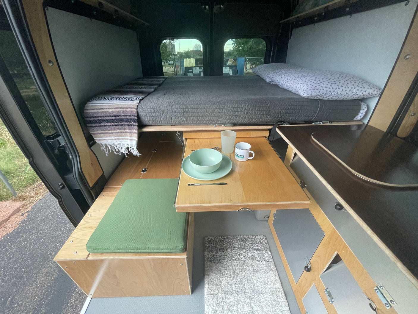 Cozy campervan interior for your next rv rental adventure, featuring a bed, dining area, and compact kitchen setup.