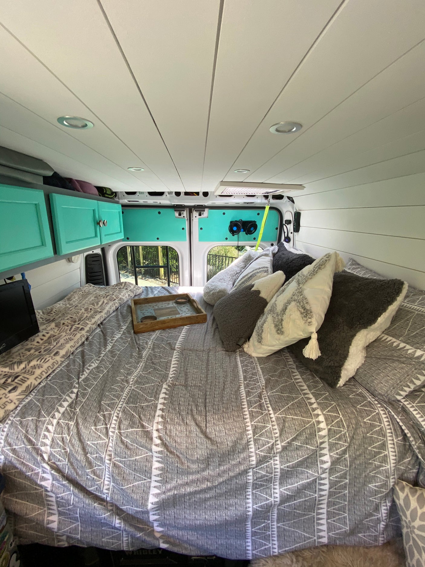 Cozy RV rental interior with bed, teal cabinets, and outdoor view. Perfect for mobile adventures.