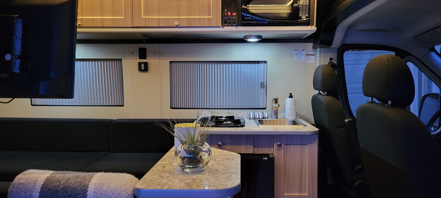 Cozy rv rental interior with a kitchenette, sofa, and front cab seats. Perfect for mobile living and travel.