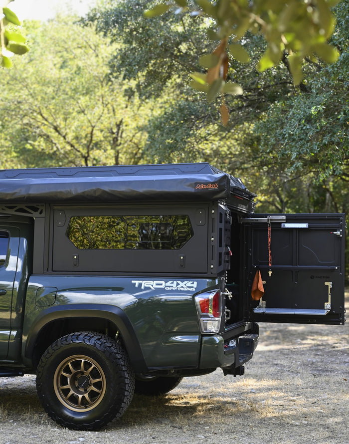 This dark green Toyota Tacoma overlanding truck with a heavy-duty truck camper & awning is great for your next RV rental adventure!