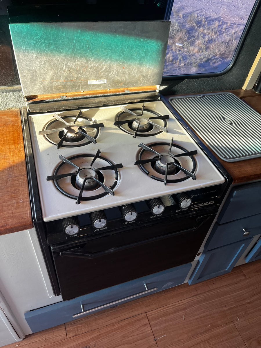 This RV rental features a vintage Magic Chef 4-burner gas stove with oven, ready for cooking on the road.