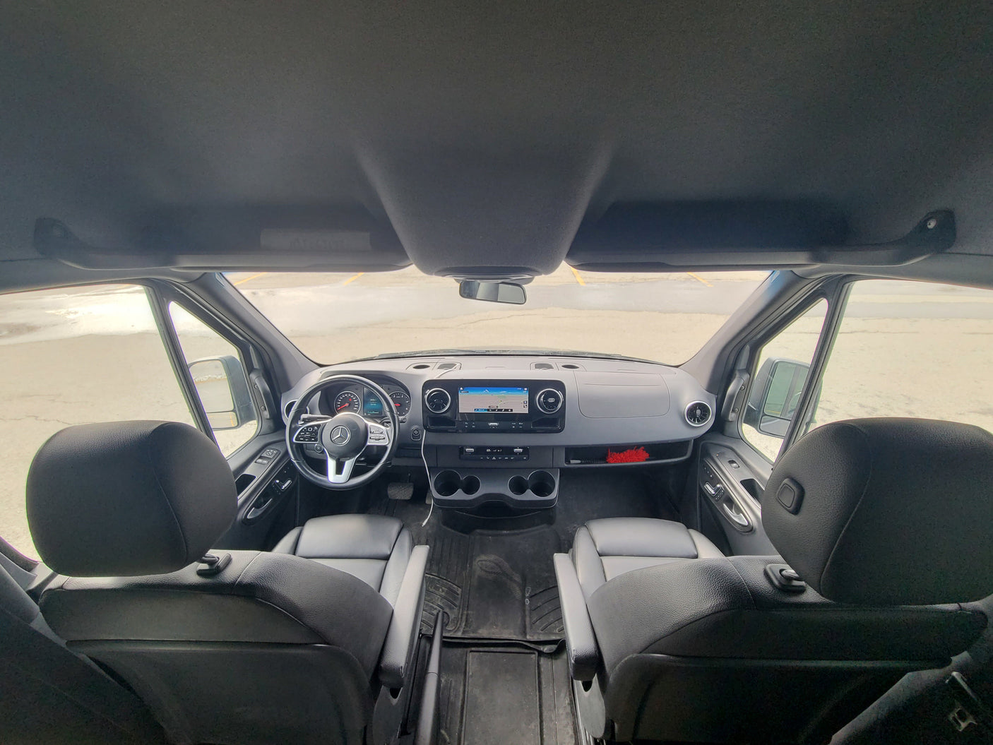 Detailed front view of a clean Mercedes-Benz Sprinter van interior, perfect for an RV rental. Dashboard, steering wheel, and navigation are visible.
