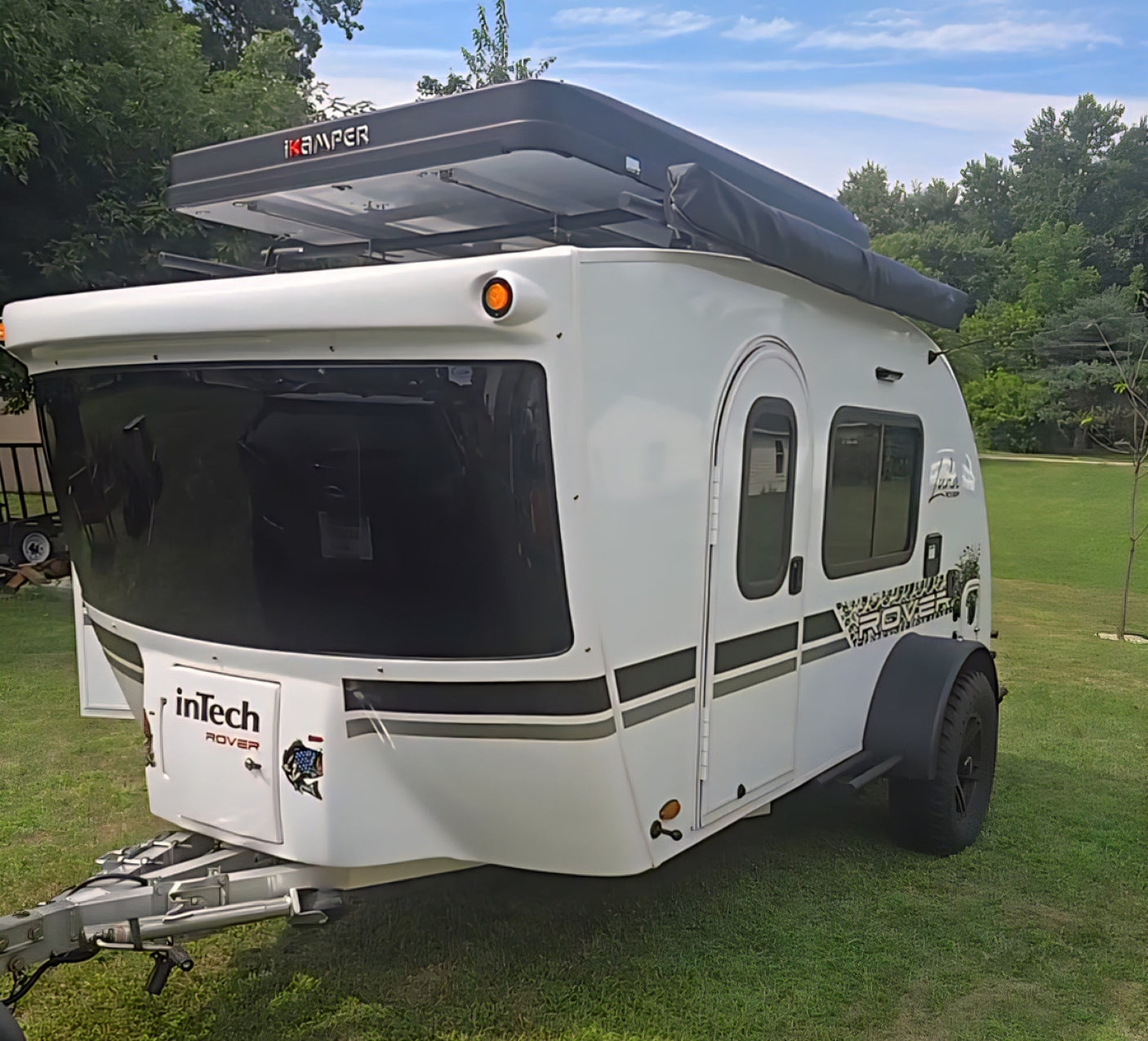A white inTech Rover travel trailer with an iKamper rooftop tent, ideal for your next rv rental adventure or off-road camping.