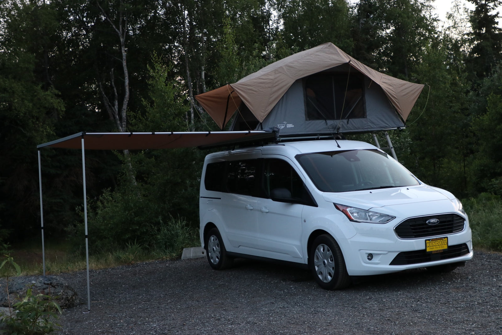 Experience outdoor adventures with this Ford Transit Connect van RV rental, featuring a rooftop tent & side awning.
