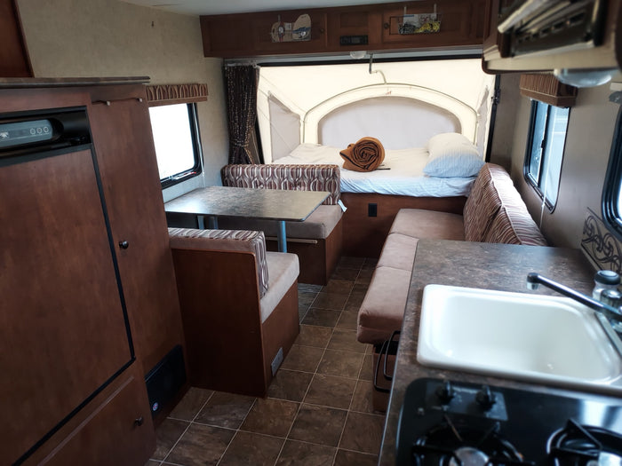 parked on a driveway under cloudy sky.|Explore this functional RV rental interior featuring a kitchen